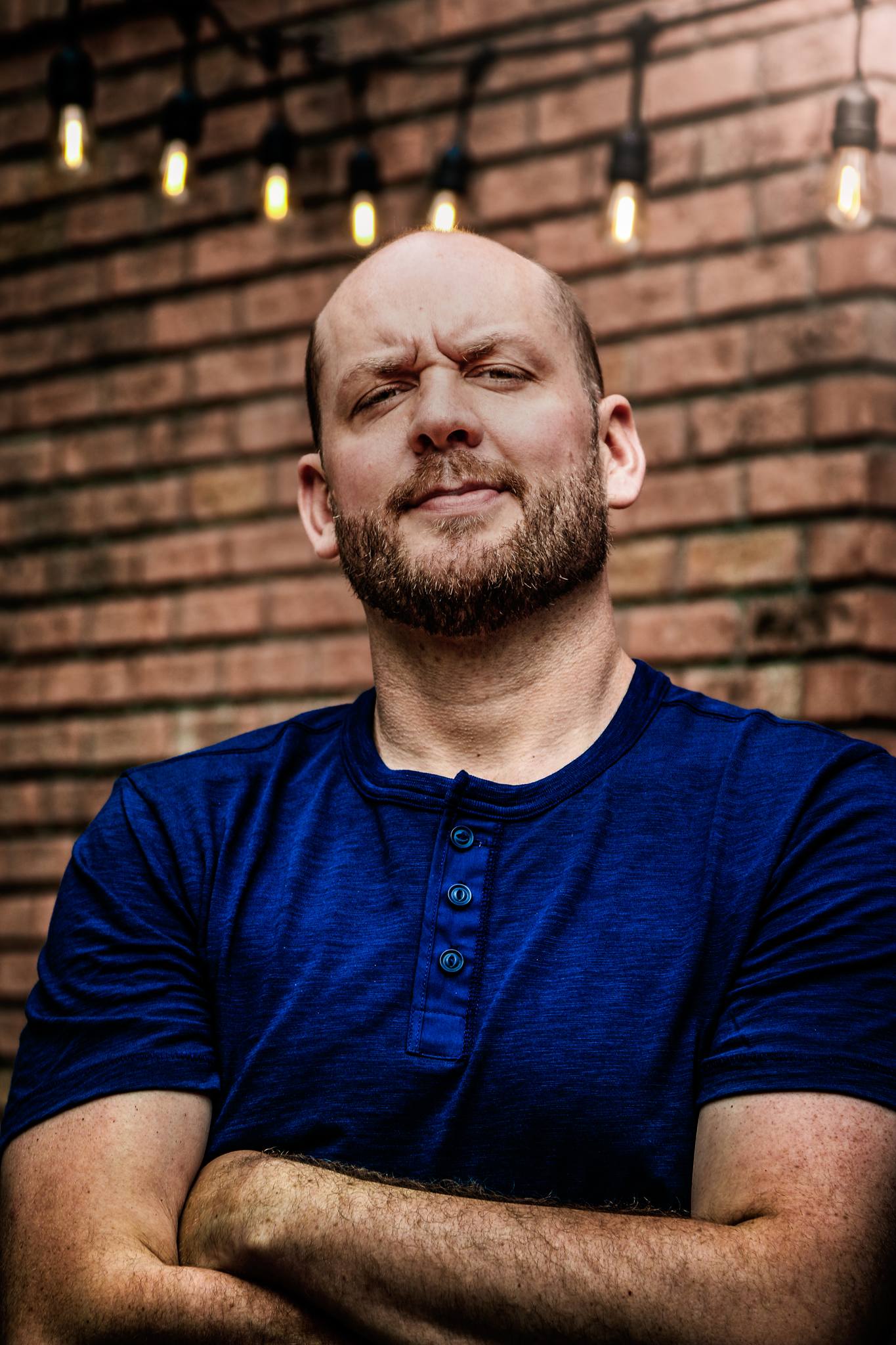 A portrait of a man in front of bricks.