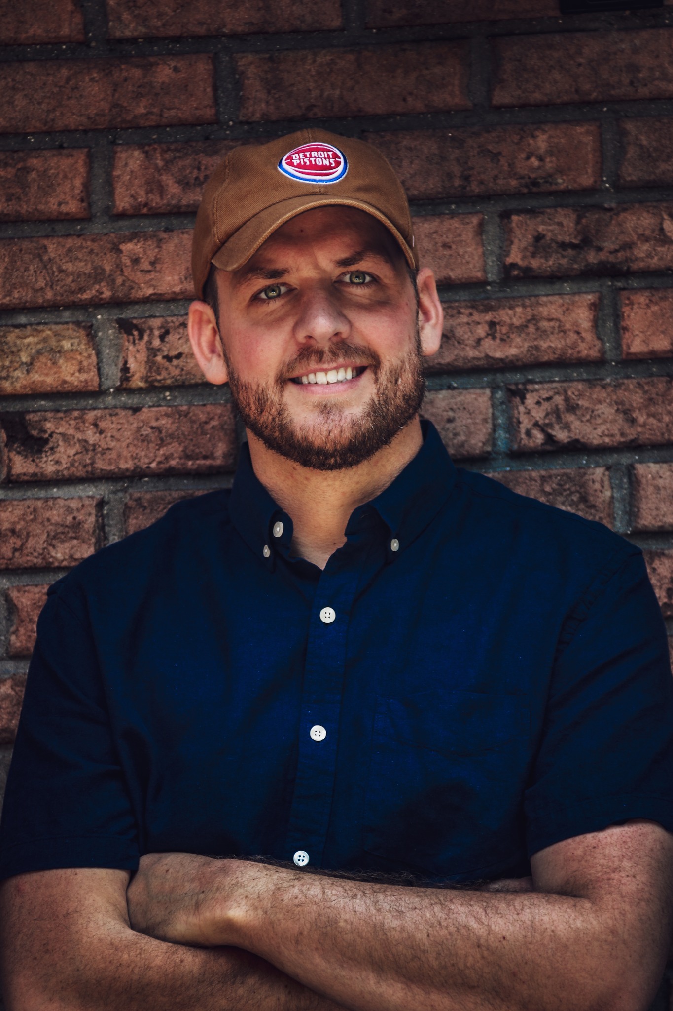 A portrait of a man against a brick wall.