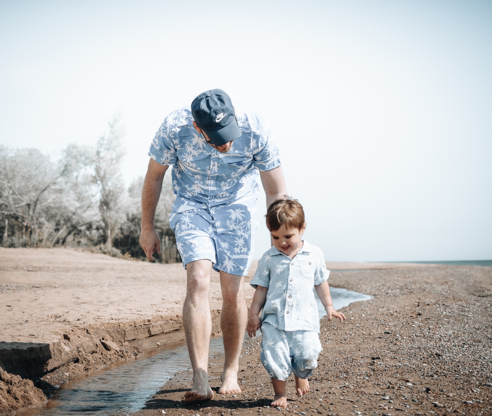 A father and child walking on a beach.