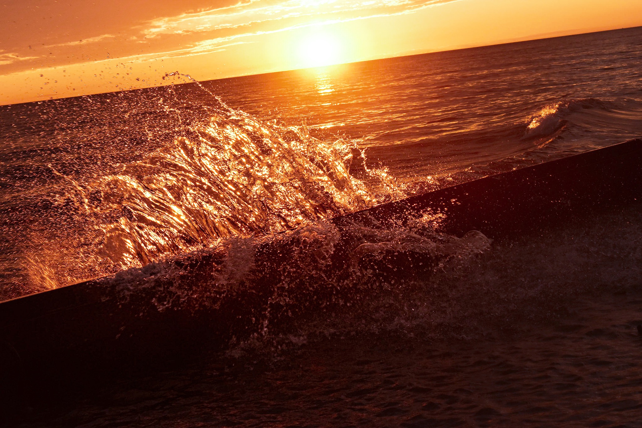 A wave crashes against a barrier.