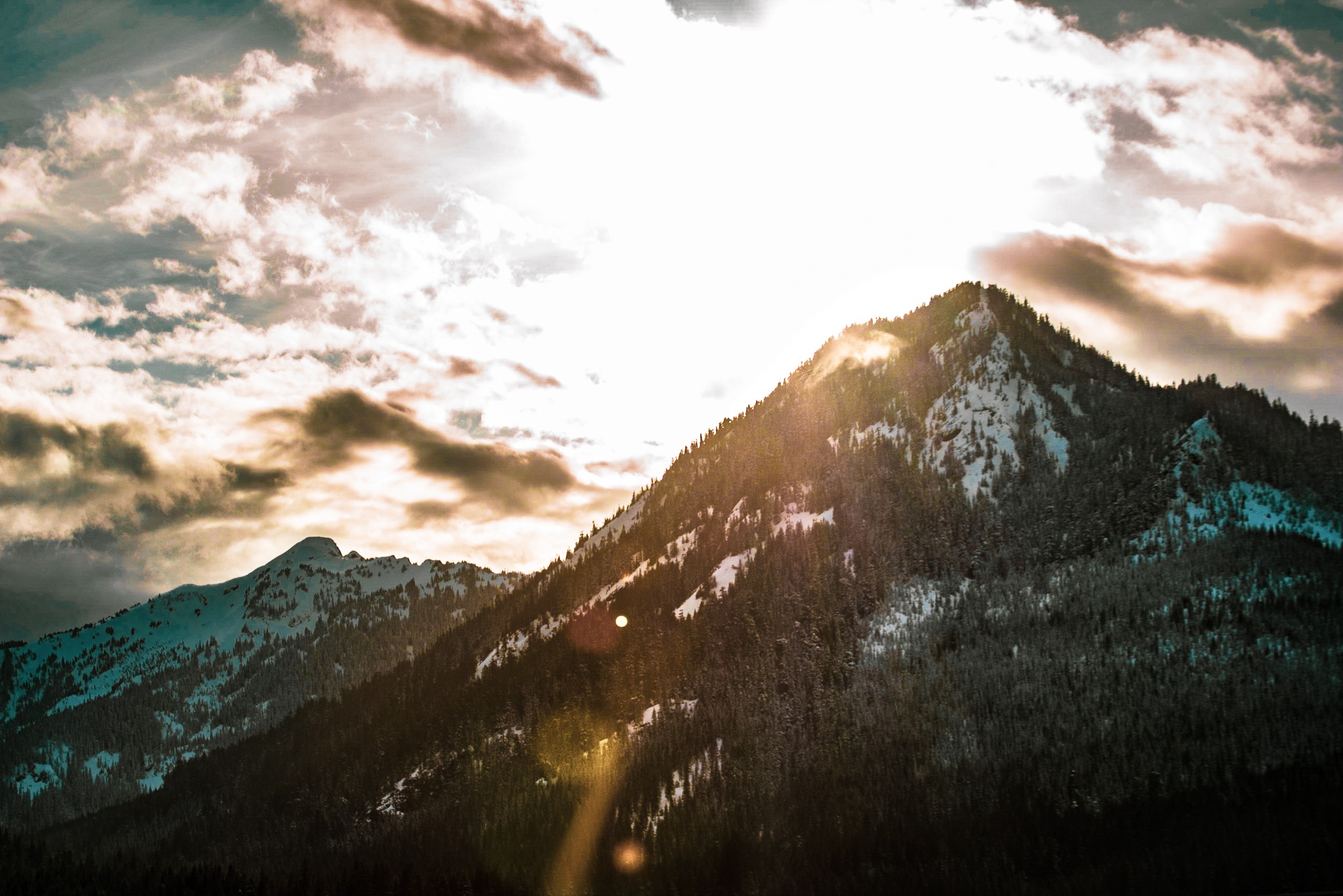 The sun radiates off of a mountain peak.