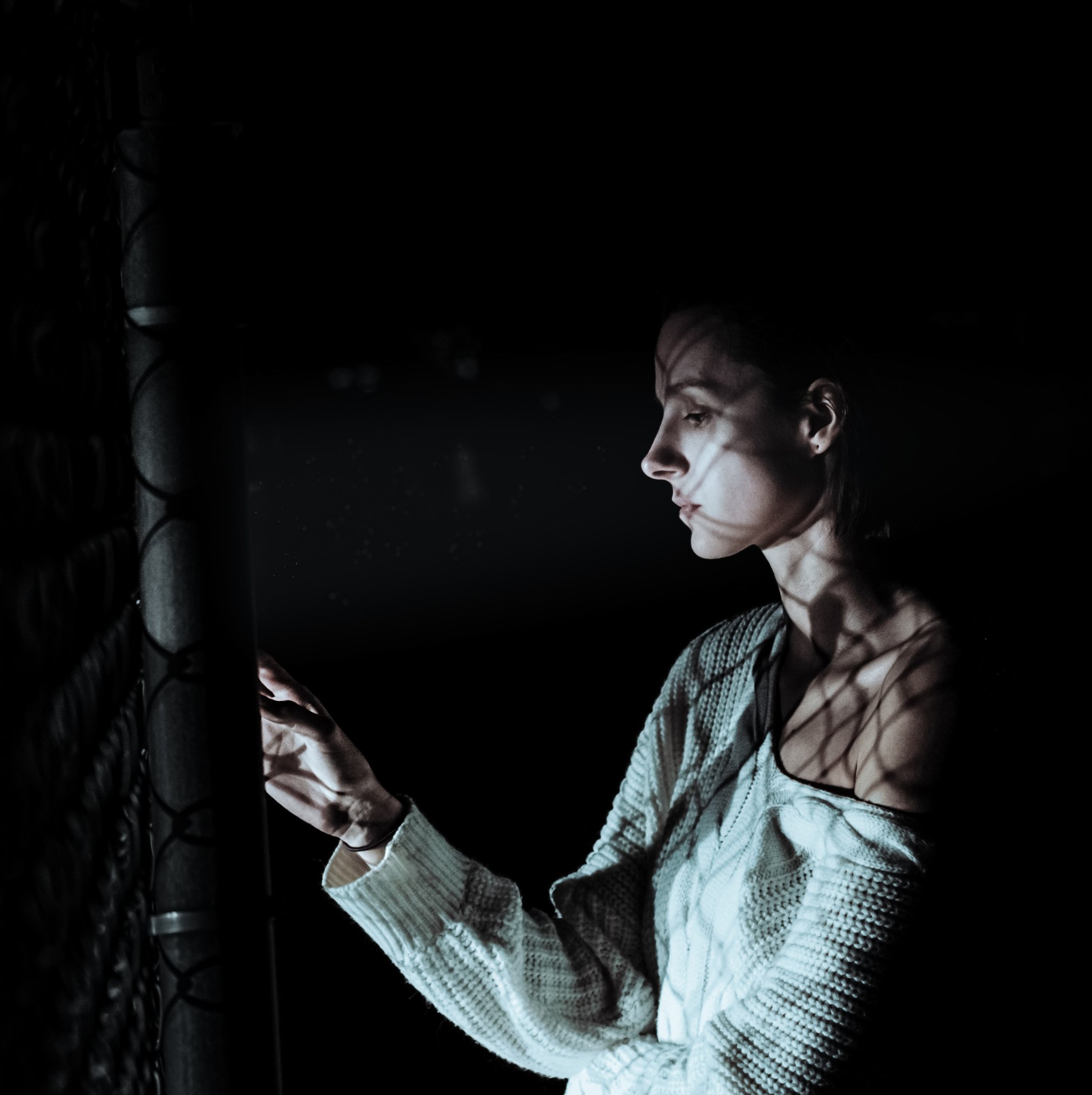 A woman standing by a fence.