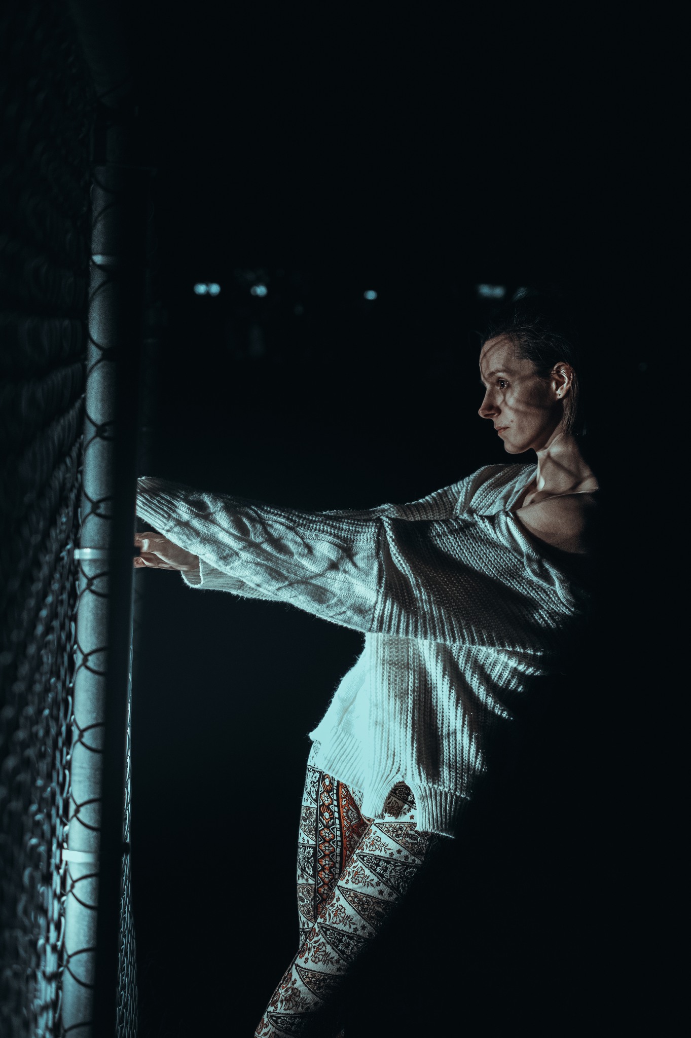 A woman standing by a fence.