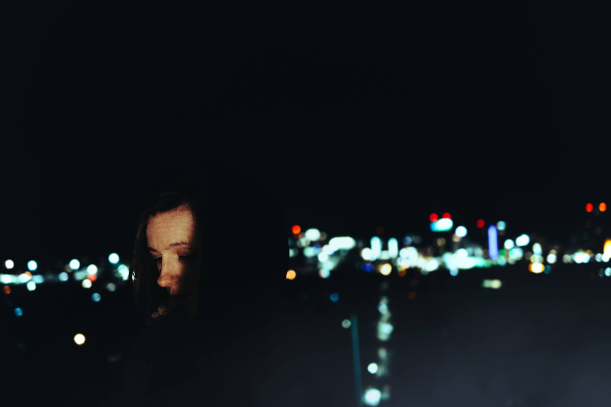 A portrait of a woman in front on a night cityscape.