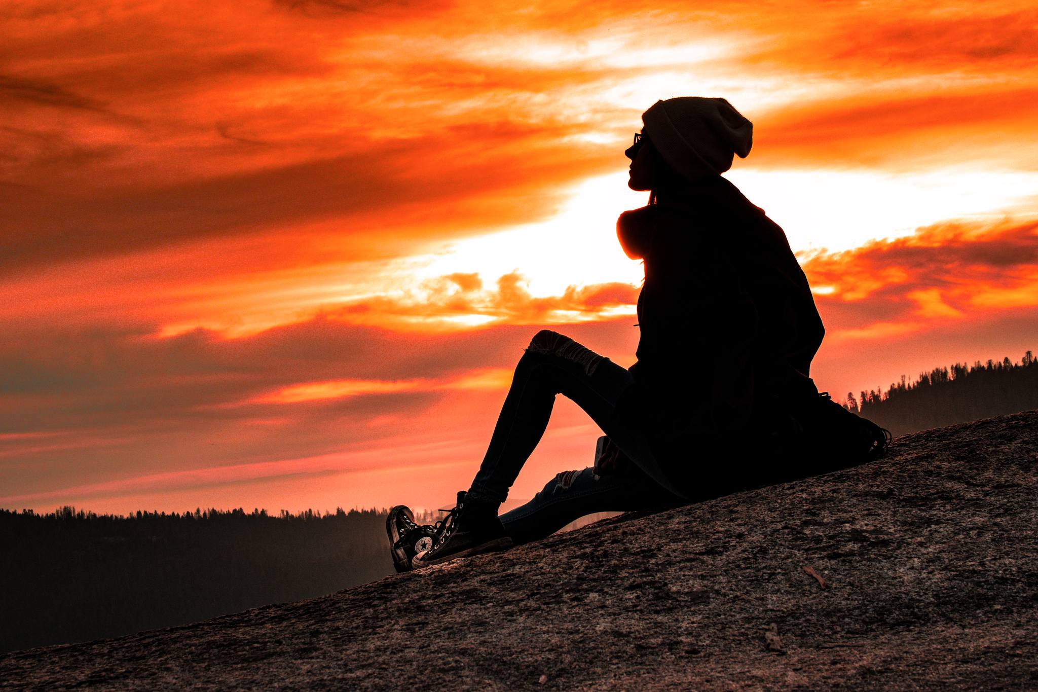 A portrait of a woman sitting on a rock.