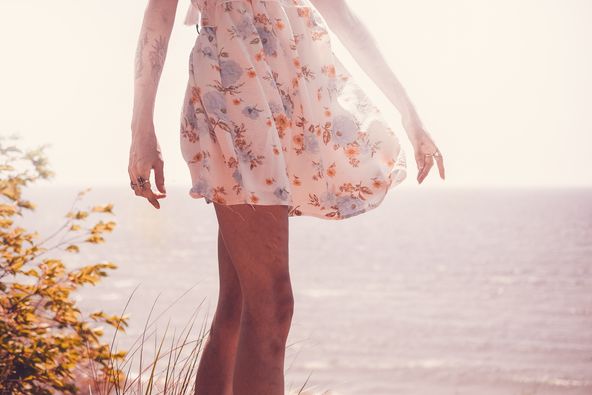 A woman dancing during golden hour on the beach.