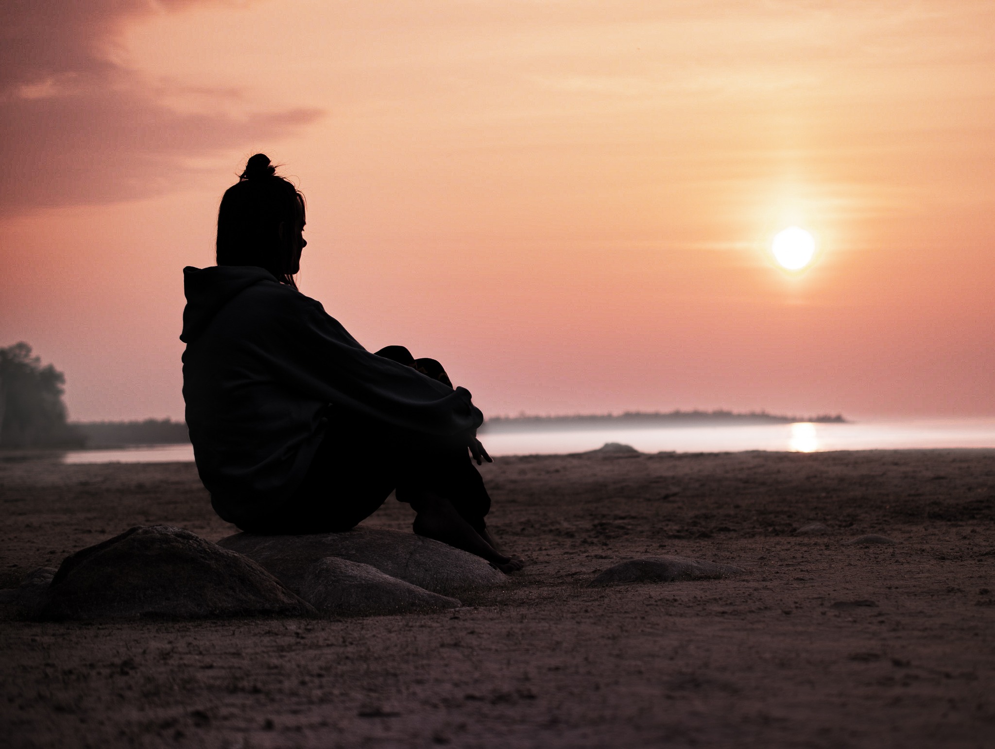 A silhouette of a woman resting at sunset.